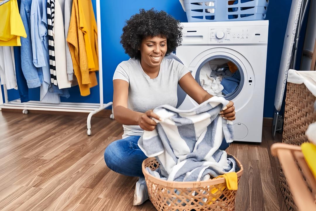 Black woman washing clothes and smiling in now laundry