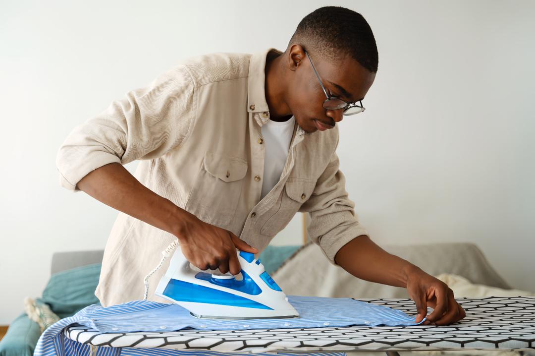 Presser man ironing clothes in now laundry