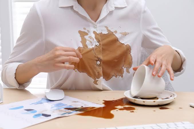 Brown coffee poured on the table and the white shirt
